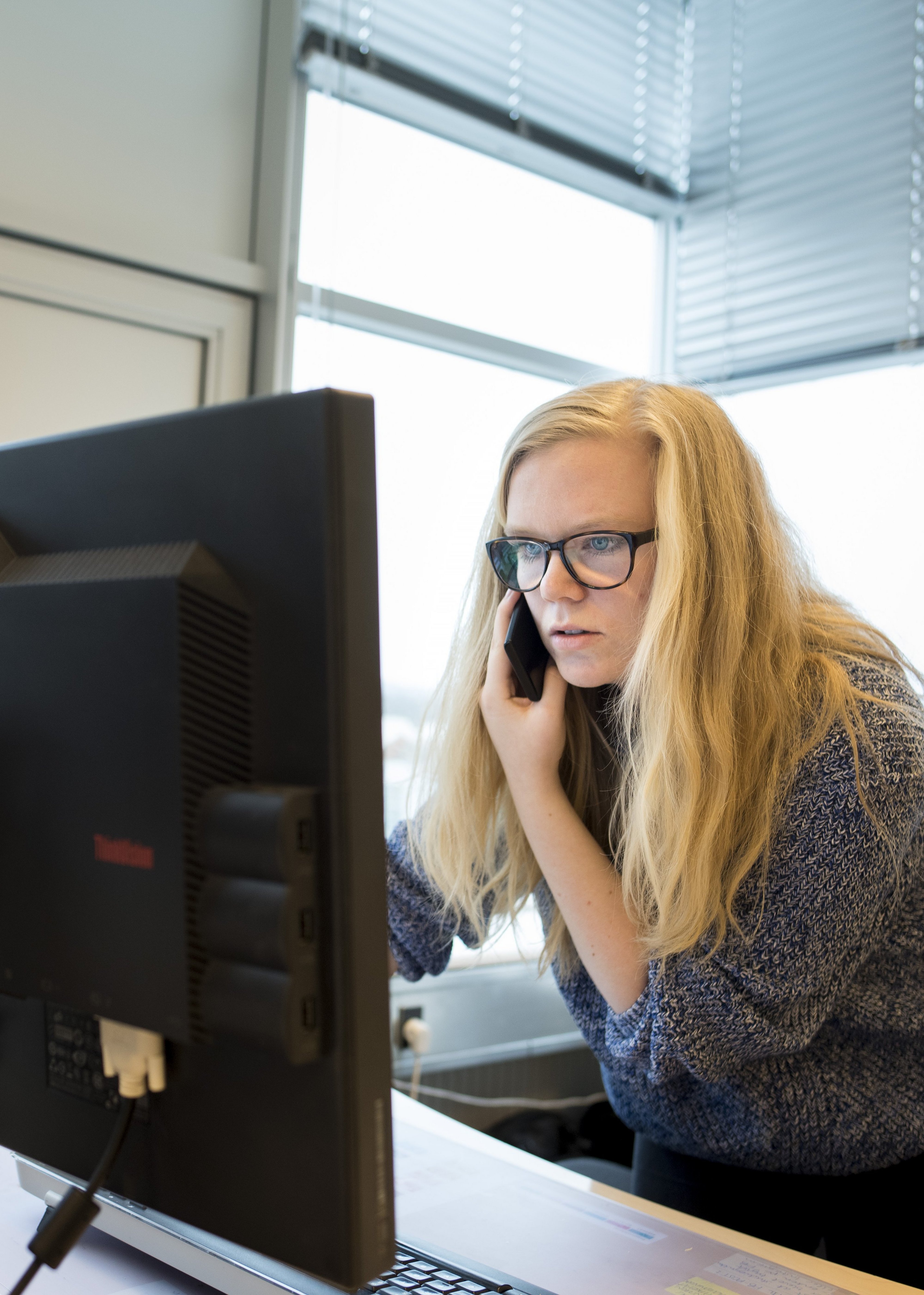 Kvinde der taler i telefon ved computersærm.