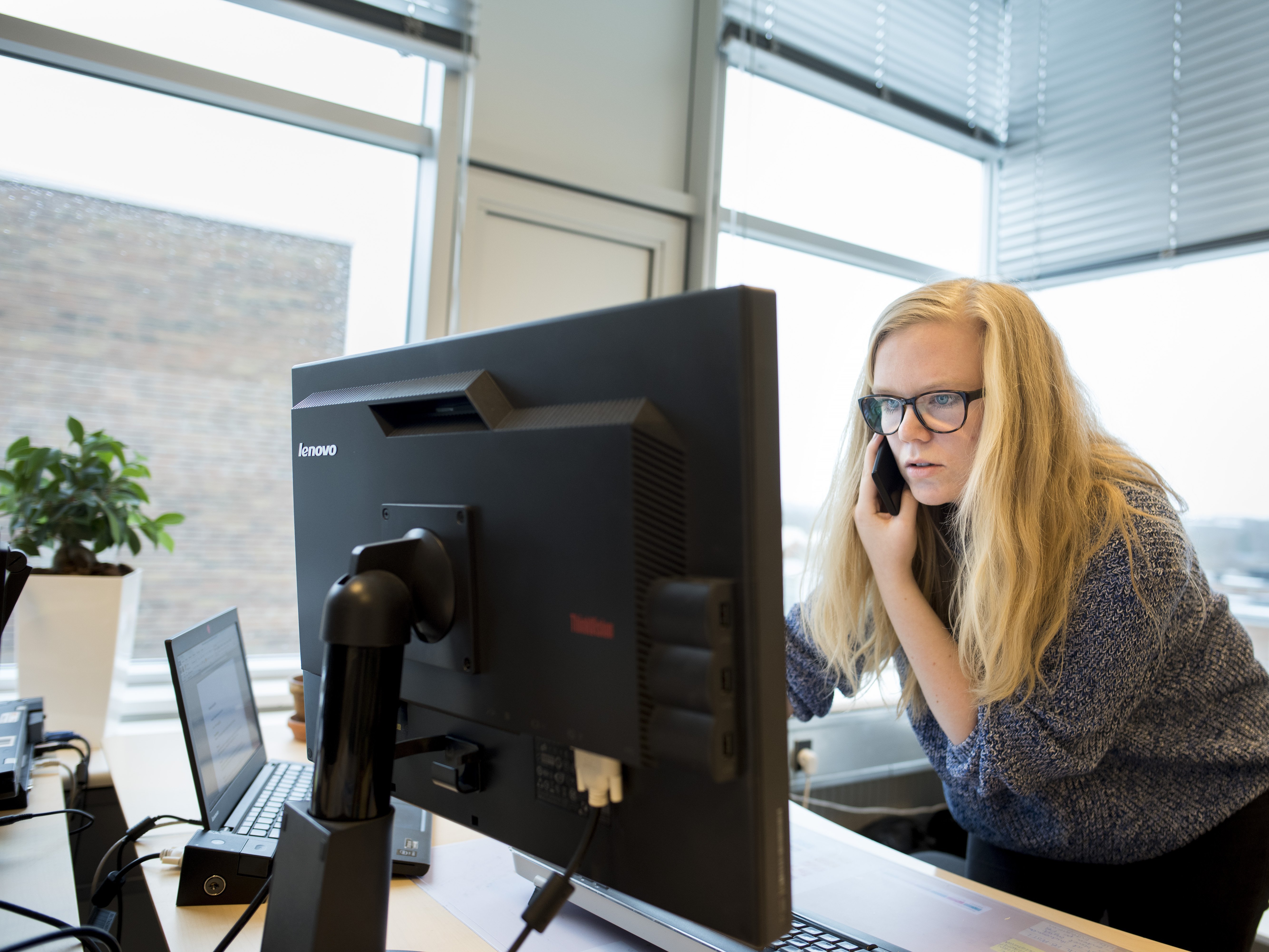 Kvinde der taler i telefon ved computersærm.